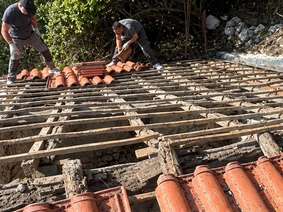 Dépose de la couverture en cours : liteaunage ancien dégarni et tuiles empilées sur le rampant